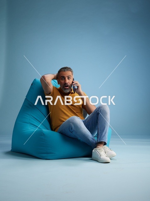 رجل سعودي مصدوم يتحدث بالهاتف على كرسي بين باج