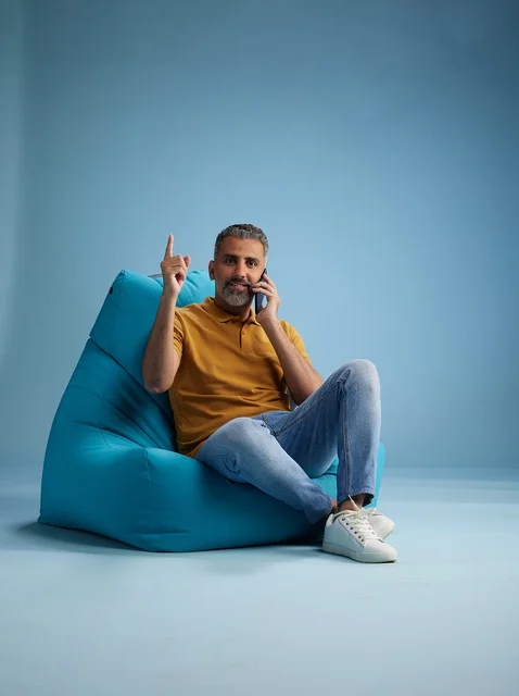 Saudi Man Talking on Smartphone on Blue Bean Bag Chair