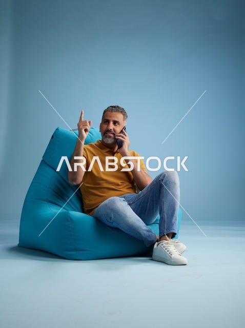 رجل سعودي يتحدث بالهاتف على كرسي بين باق