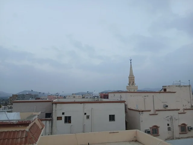 مئذنة مسجد ومباني سكنية تحت سماء غائمة بالشرق الأوسط