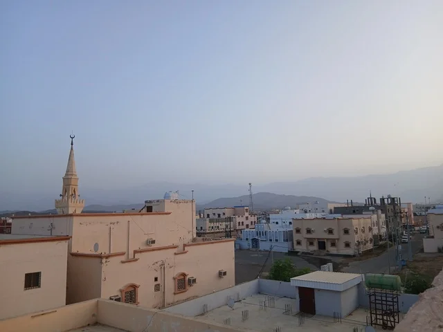 حي سكني مع مئذنة مسجد وجبال في الخلفية