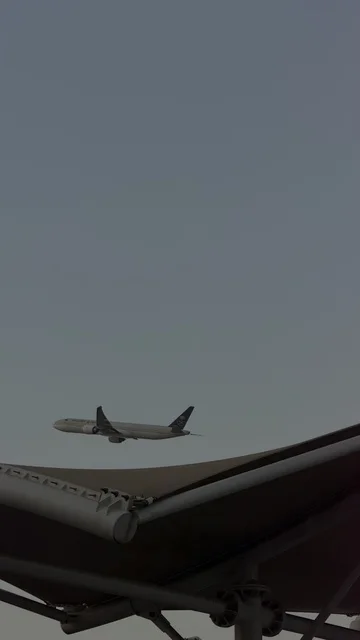 طائرة تجارية تحلق فوق هيكل معماري في سماء غائمة