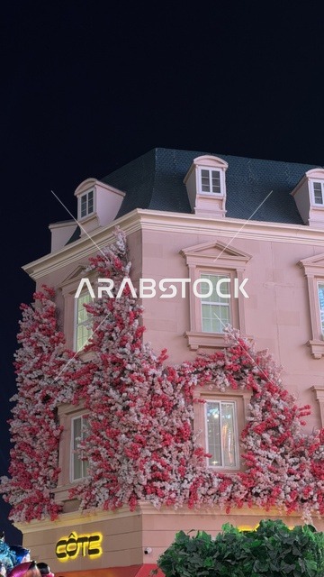 واجهة مبنى وردي مع زينة زهور في الليل