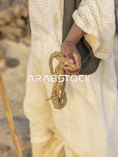 رجل سعودي يمسك بحبل تقليدي في الصحراء لقطة قريبة