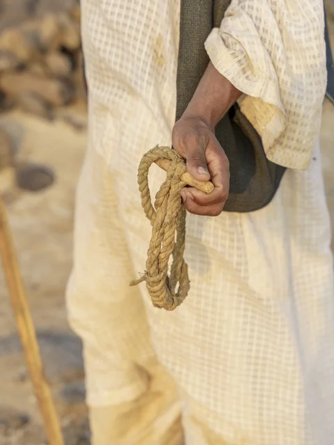 رجل سعودي يمسك بحبل تقليدي في الصحراء لقطة قريبة