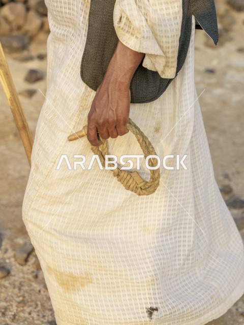 رجل سعودي يمسك بحبل الإبل بالزي التقليدي