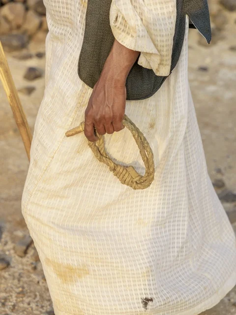 رجل سعودي يمسك بحبل الإبل بالزي التقليدي