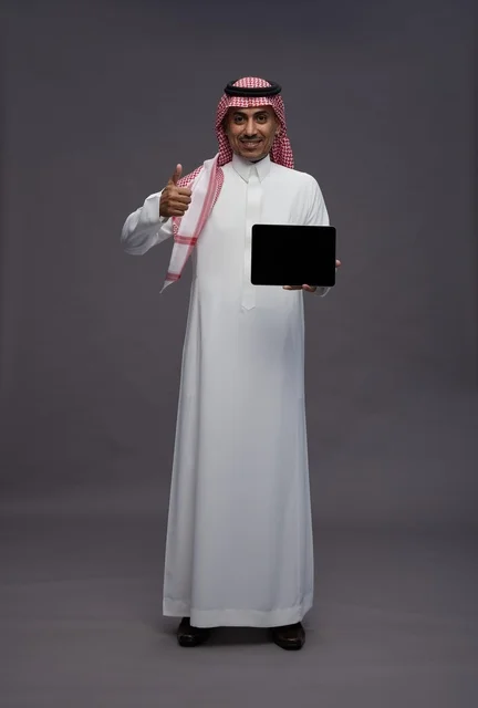 رجل سعودي يمسك جهاز لوحي مع إيماءة الإعجاب