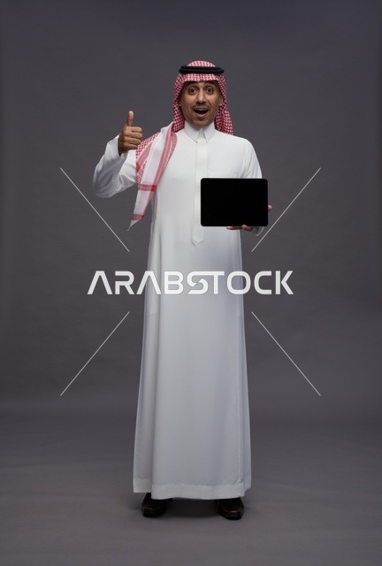 رجل سعودي مع جهاز لوحي وإيماءة الإعجاب