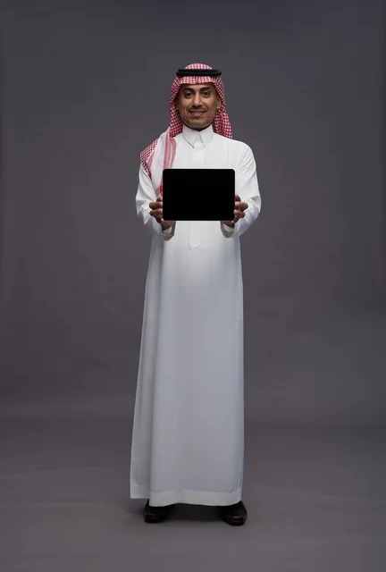 رجل سعودي يحمل جهاز لوحي رقمي في لقطة استوديو احترافية