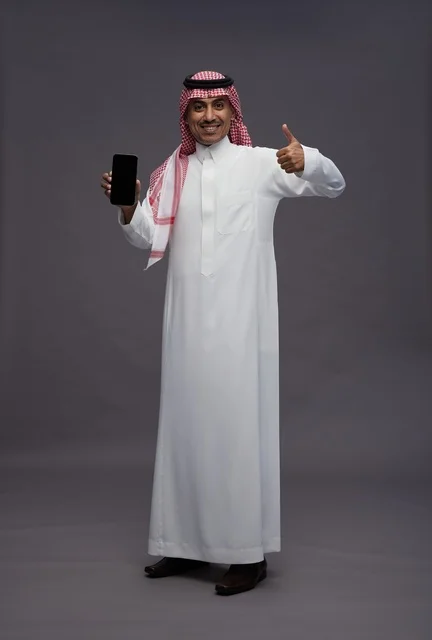 رجل سعودي يمسك هاتف ذكي مع إيماءة الإعجاب