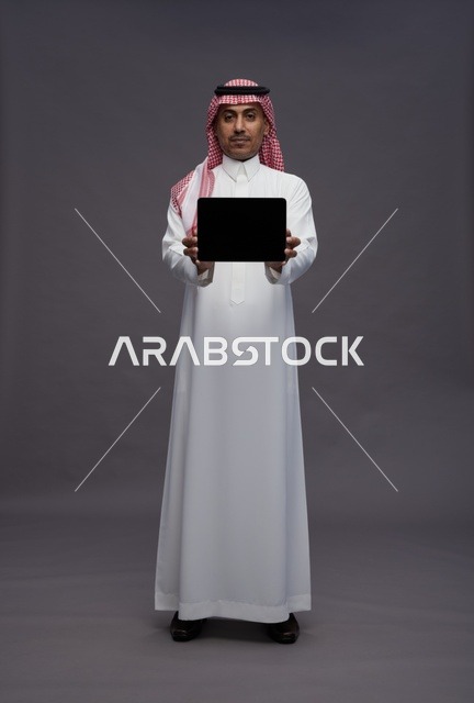 Saudi Man in Traditional Thobe Holding Digital Tablet