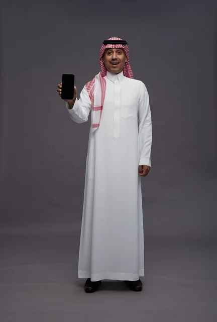 رجل سعودي يحمل هاتف ذكي بتعبير وجه مندهش