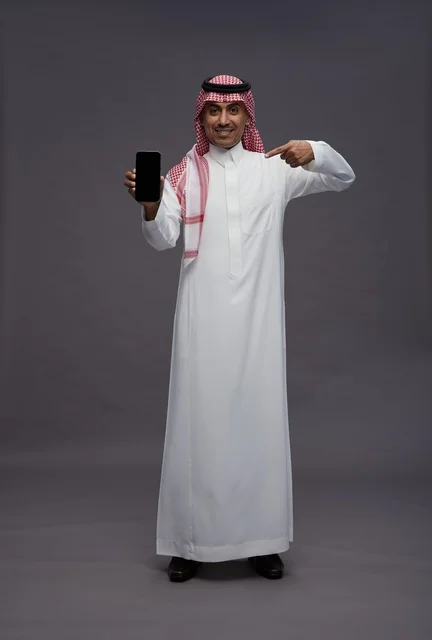 رجل سعودي يحمل هاتف ذكي ويشير إلى الشاشة
