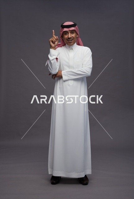 رجل سعودي بالزي التقليدي يشير بإصبعه للأعلى