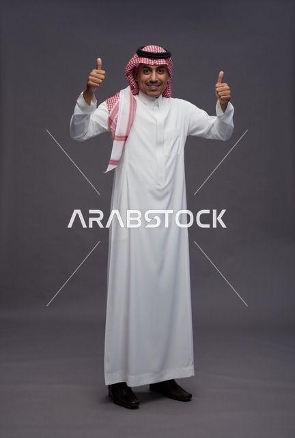 رجل سعودي بالزي التقليدي يشير بعلامة الإعجاب