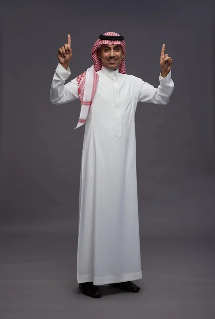 رجل سعودي بالثوب التقليدي يشير إلى الأعلى
