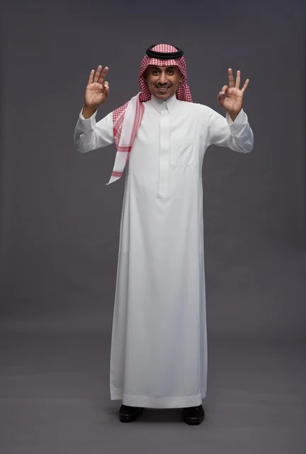 Saudi Man in Traditional White Thobe on Grey Background - Photo