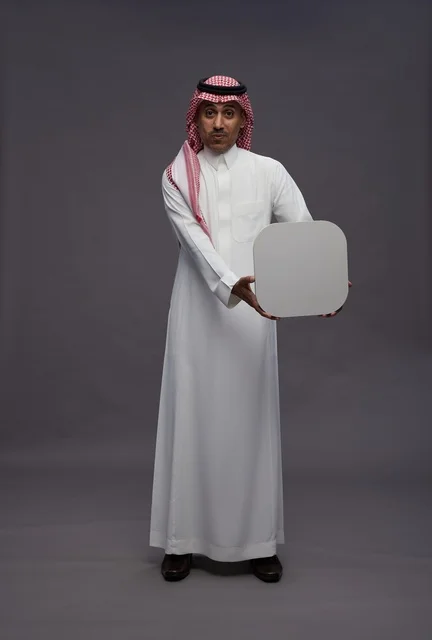 رجل سعودي بالثوب التقليدي يحمل لوحة بيضاء فارغة