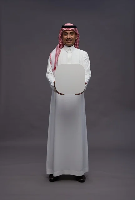 رجل سعودي يحمل لوحة بيضاء فارغة في الاستوديو