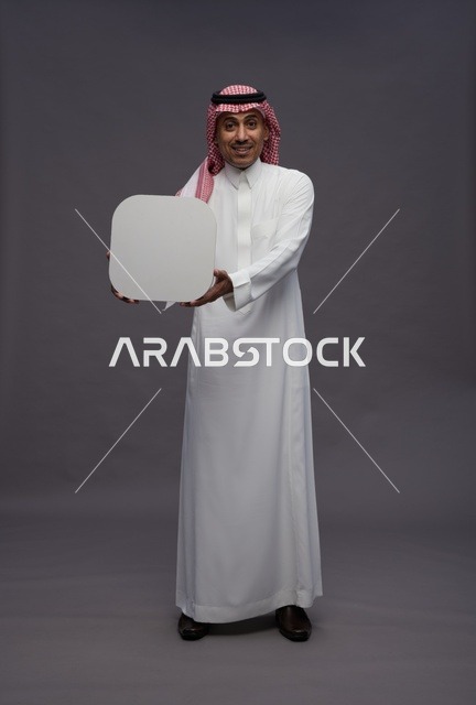 Saudi Man Holding Blank Speech Bubble in Gray Studio