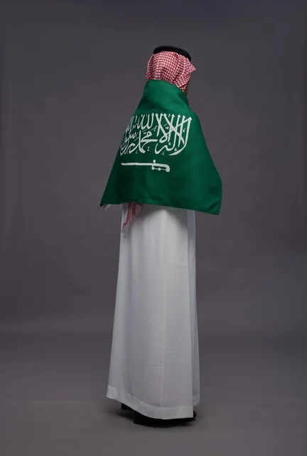 رجل سعودي بالعلم من الخلف في استوديو