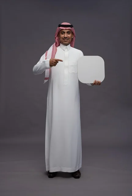 رجل سعودي بالزي التقليدي يمسك لوحة بيضاء فارغة