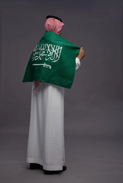Saudi Man in Traditional Dress with National Flag Saudi Man in Traditional Dress with National Flag