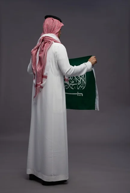 رجل سعودي يحمل علم المملكة بالزي التقليدي
