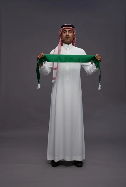 رجل سعودي يحمل وشاح علم المملكة العربية السعودية