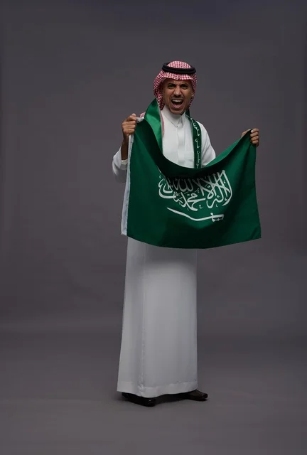 رجل سعودي يحمل علم المملكة العربية السعودية في استوديو