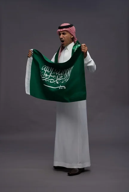 رجل سعودي يحمل العلم الوطني في استوديو