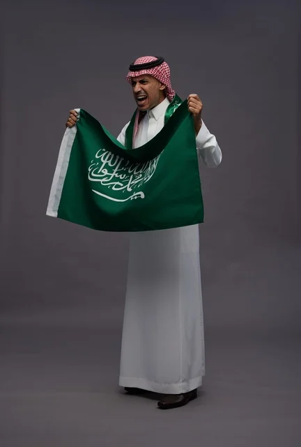 رجل سعودي يحمل علم المملكة العربية السعودية بحماس