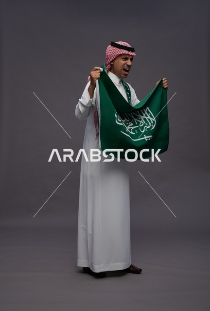 رجل سعودي يحمل علم السعودية في اليوم الوطني