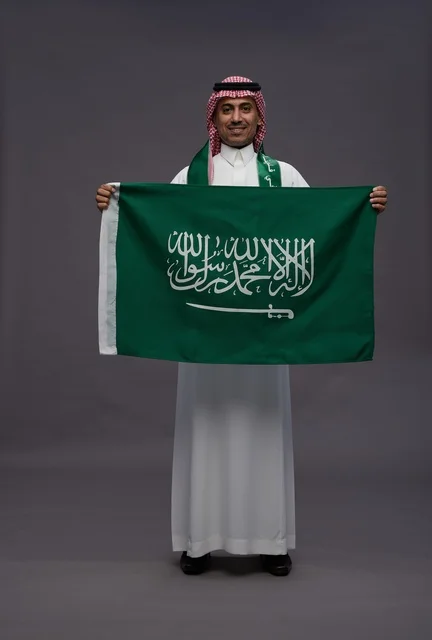 رجل سعودي يحمل علم المملكة العربية السعودية