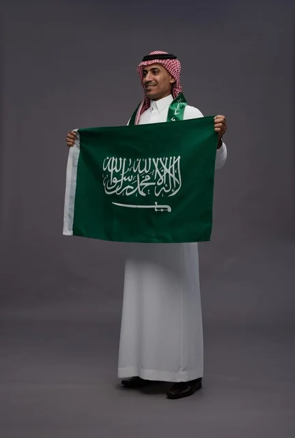 رجل سعودي يحمل علم المملكة العربية السعودية