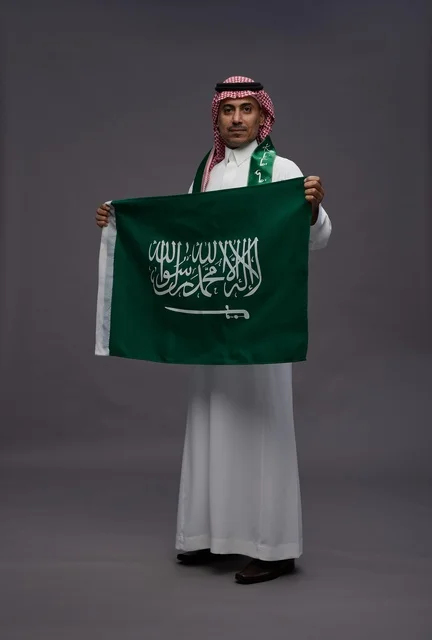 رجل سعودي يحمل علم المملكة العربية السعودية