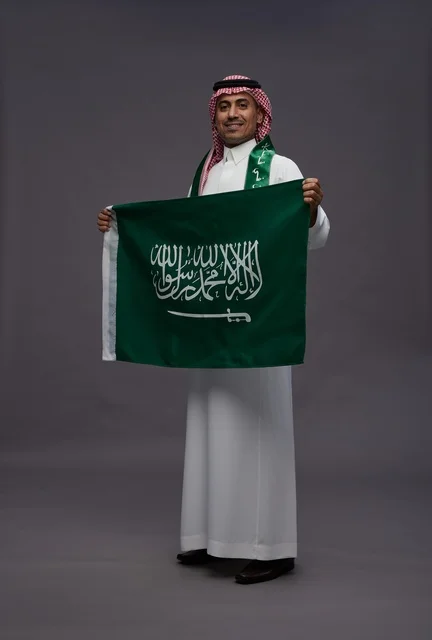 رجل سعودي يحمل علم المملكة العربية السعودية