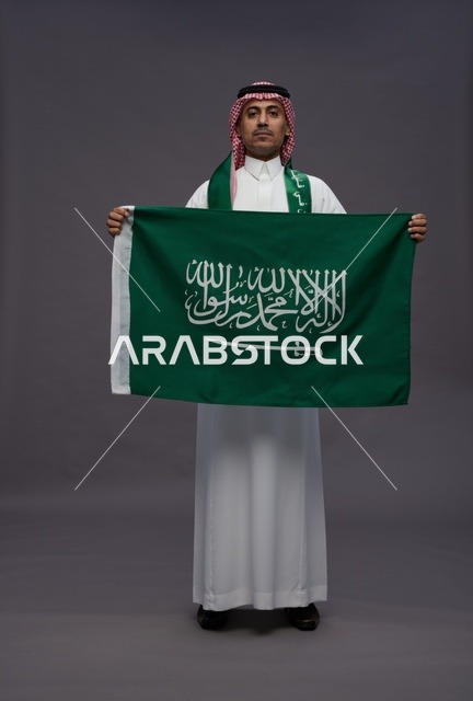 رجل سعودي يحمل علم المملكة العربية السعودية