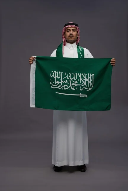 رجل سعودي يحمل علم المملكة العربية السعودية