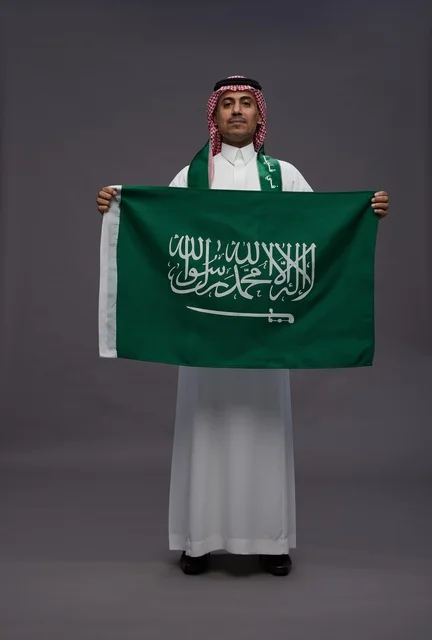 رجل سعودي يحمل علم المملكة في استوديو