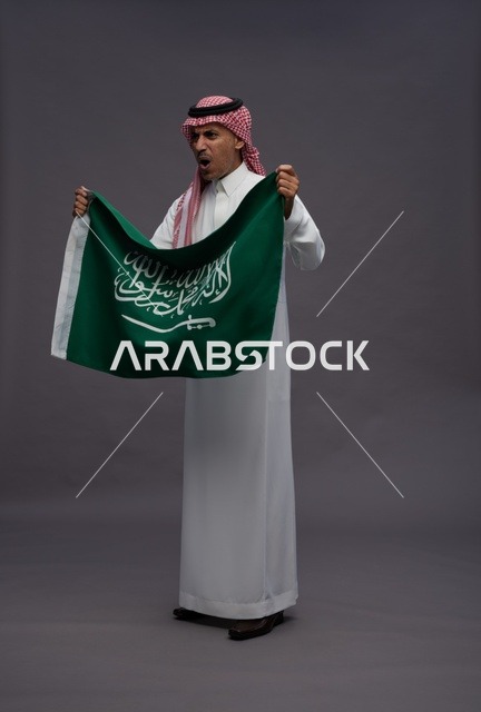رجل سعودي يحمل علم السعودية في الاستوديو