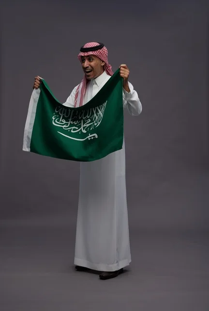 رجل سعودي يحمل علم المملكة العربية السعودية في الاستوديو