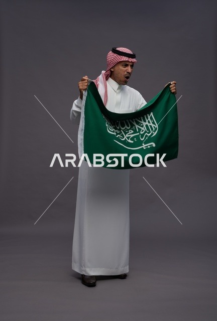 رجل سعودي يحمل علم المملكة العربية السعودية باليوم الوطني
