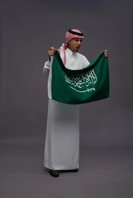 رجل سعودي يحمل علم المملكة العربية السعودية باليوم الوطني