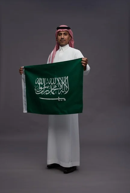 مواطن سعودي يحمل علم المملكة العربية السعودية في استوديو