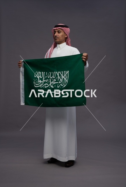رجل سعودي يحمل علم المملكة العربية السعودية في استوديو