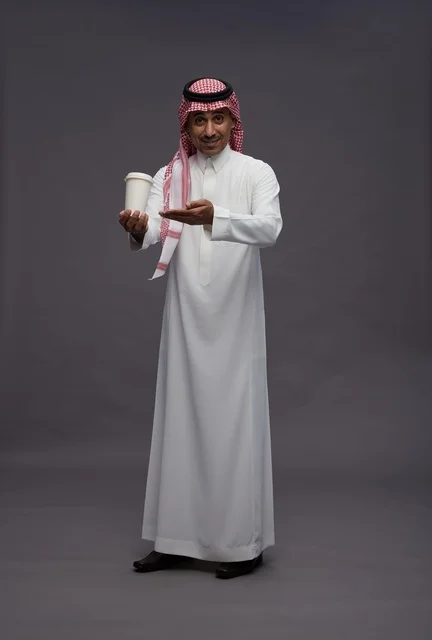 رجل سعودي بالزي التقليدي يحمل كوب قهوة