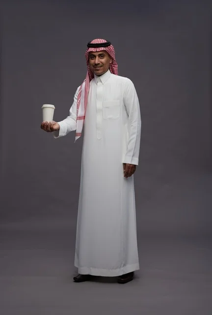 رجل سعودي بالزي التقليدي يحمل كوب قهوة
