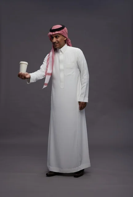 رجل سعودي بالزي التقليدي يحمل كوب قهوة